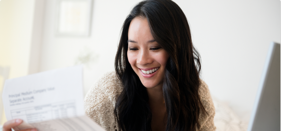 A young woman smiles with delight while reading a financial document.